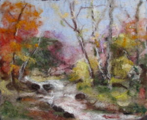 Ginger Summit landscape in felt. A bubbling stream with trees showing autumn foliage of reds and oranges.