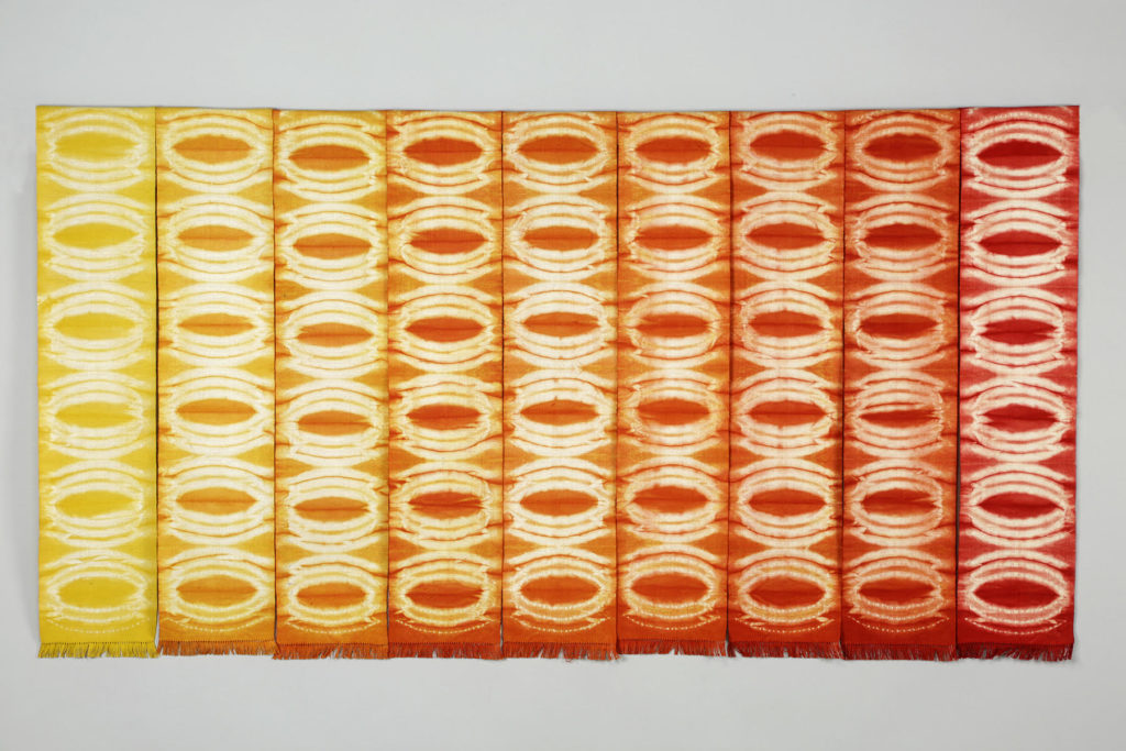 Series of handwoven panels dyed in a range of color from yellow on the left to scarlet on the right, using shibori technique.
